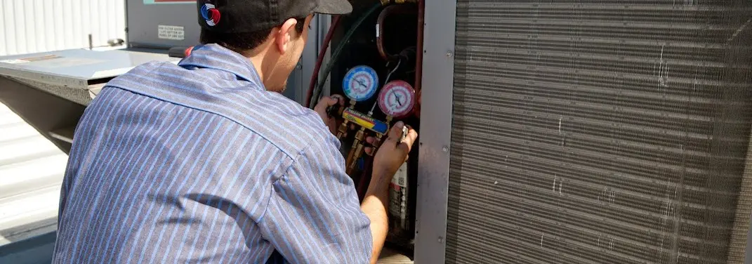 HVAC technician servicing a condenser unit in Reading